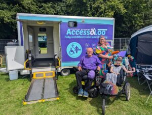 Michael and service users outside AccessoLoo Lilia at the WOMAD Festival